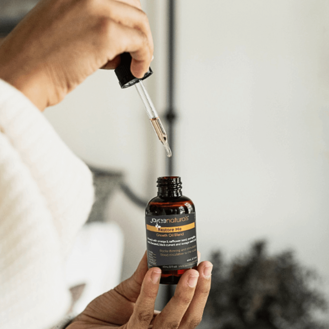 Woman holding a bottle of Restore Me with the dropper containing some oil