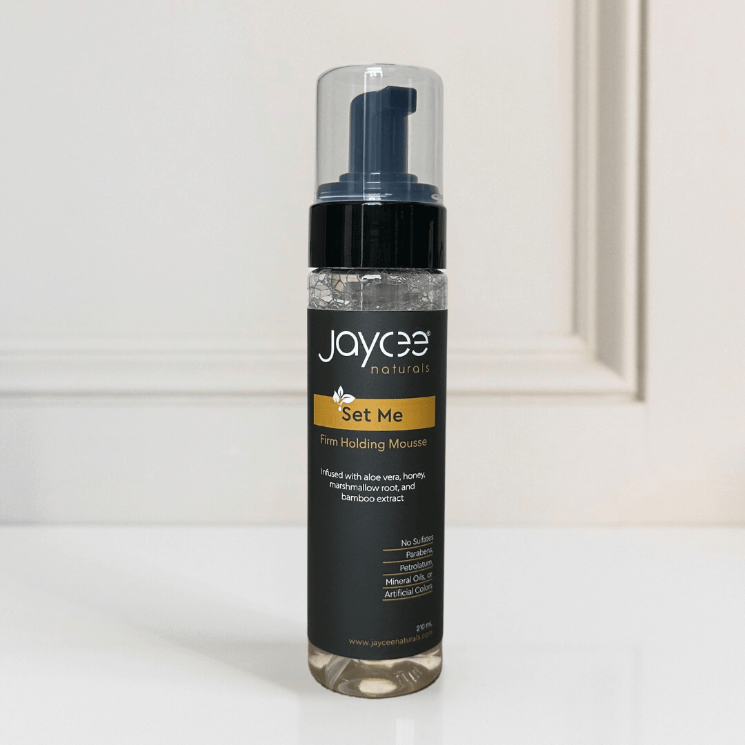 Jaycee Naturals Set Me Firm Holding Mousse, with honey, aloe vera, and marshmallow root extract. 210 mL bottle standing on a white countertop.