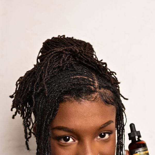 A woman smiling with a loc updo hairstyle