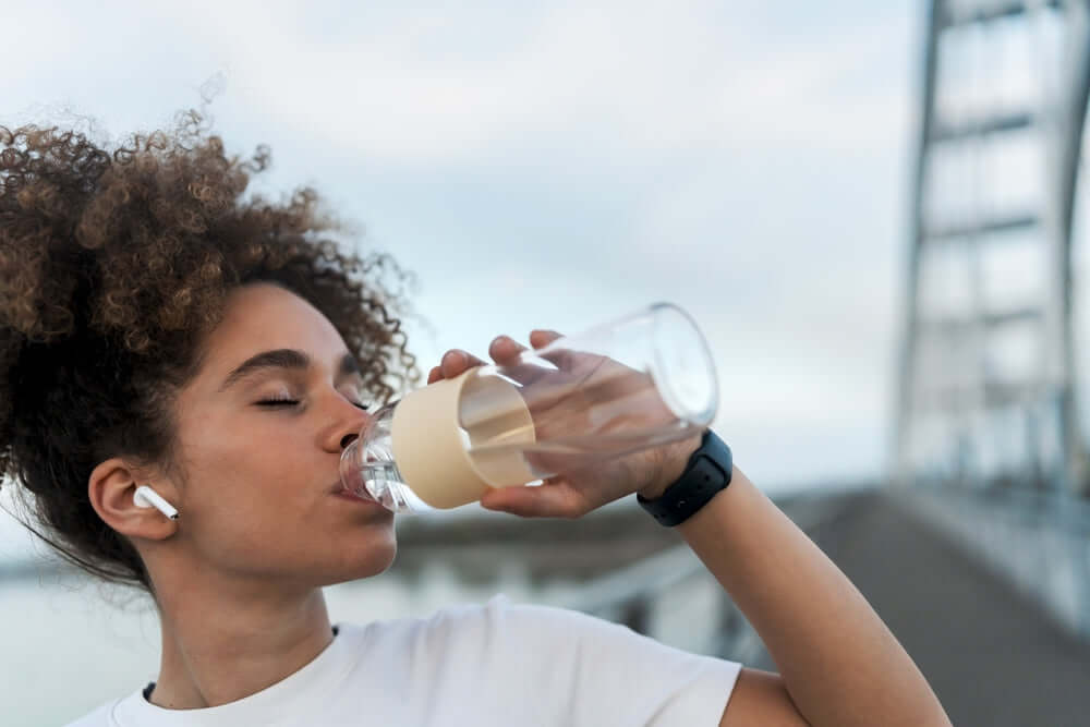A woman with curly hair drinking water