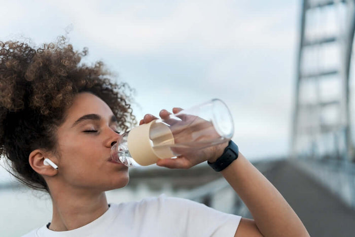 A woman with curly hair drinking water