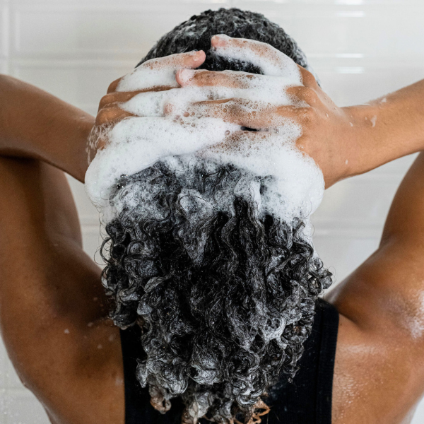 Person washing their hair with soap suds in a bathroom setting