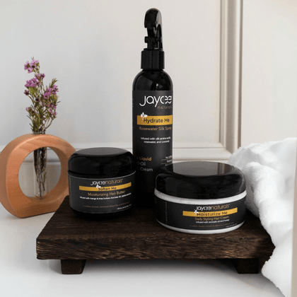 Hair care set for moisturizing the hair, including Hydrate Me Rosewater Silk Spray, Soften Me Hair Butter, and Moisturize Me Hair Cream. One bottle or jar of each product, standing together in a group on a white countertop.