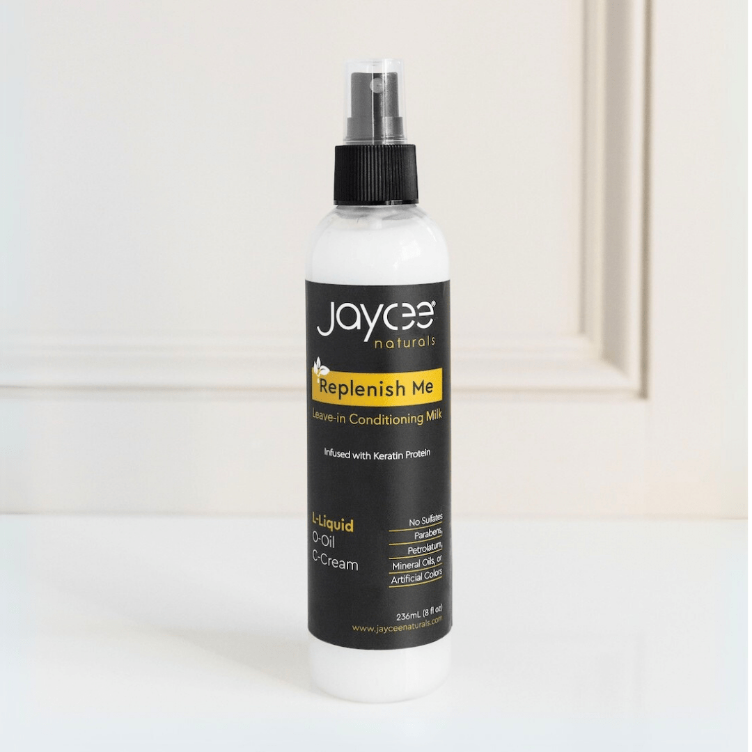 Jaycee Naturals Replenish Me Leave-In Conditioning Milk, infused with keratin protein and free of sulfates, parabens, petrolatum, mineral oils, and artificial colors. 236ml bottle standing on a white countertop.