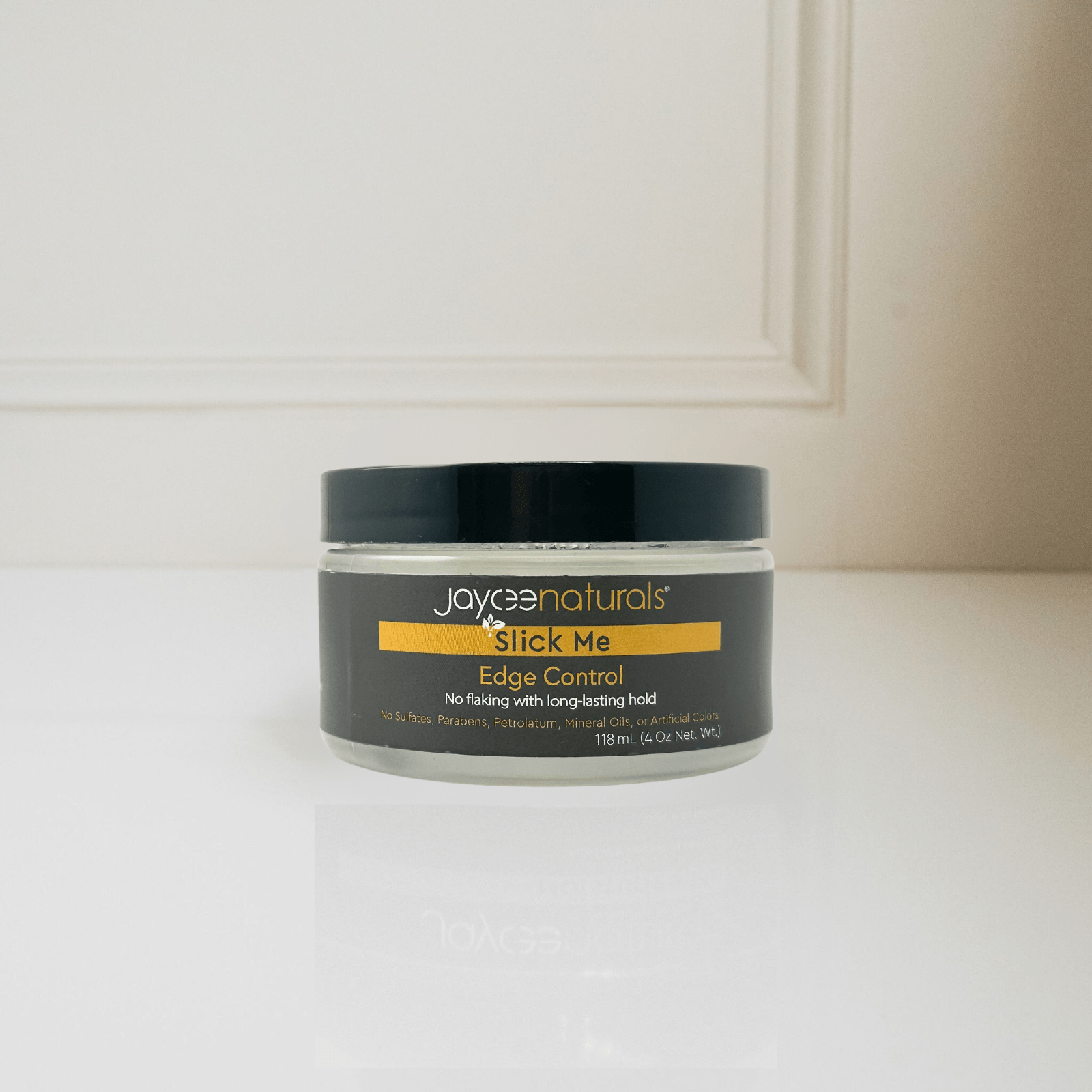 Jaycee Naturals Slick Me Edge Control, provides a lasting hold and free of sulfates, parabens, petrolatum, mineral oils, and artificial colors. 118ml jar standing on a white countertop.