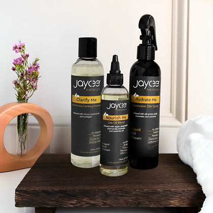 Three Jaycee natural skincare products on a wooden surface with a vase of flowers in the background.