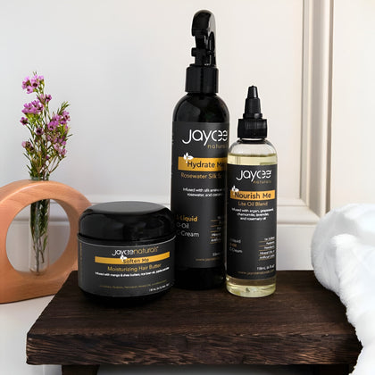 Jaycee Naturals hair care products on a wooden surface with a vase of flowers in the background.