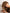 a model with loose, curly red hair moved towards her face and holding her head down with her fingers in her hair